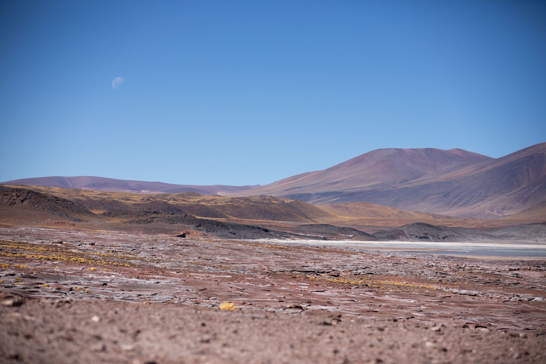 Deserto vermelho com lua sobre montanhas no horizonte