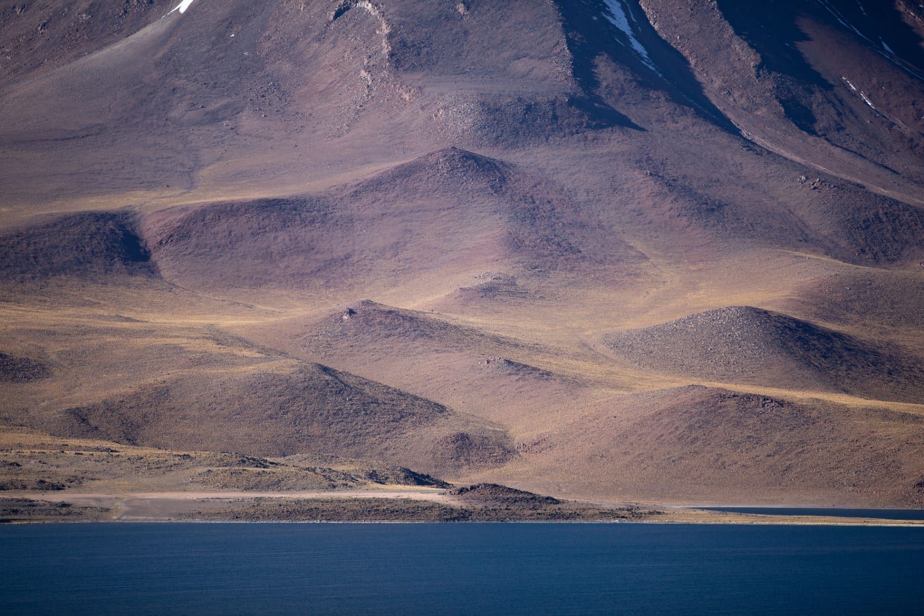 Relevo suave de montanha refletido sobre lago azul profundo