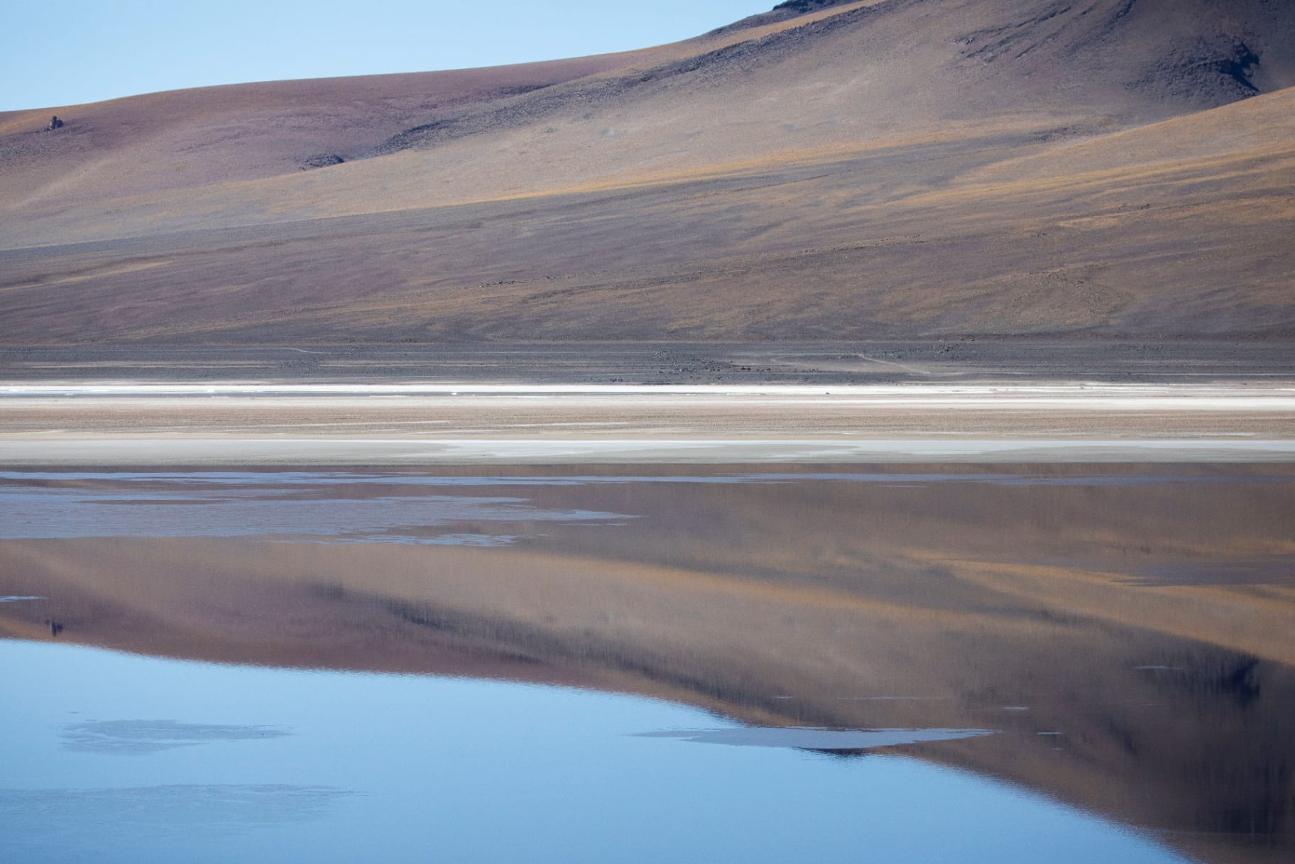 Encosta dourada refletida em laguna calma do altiplano