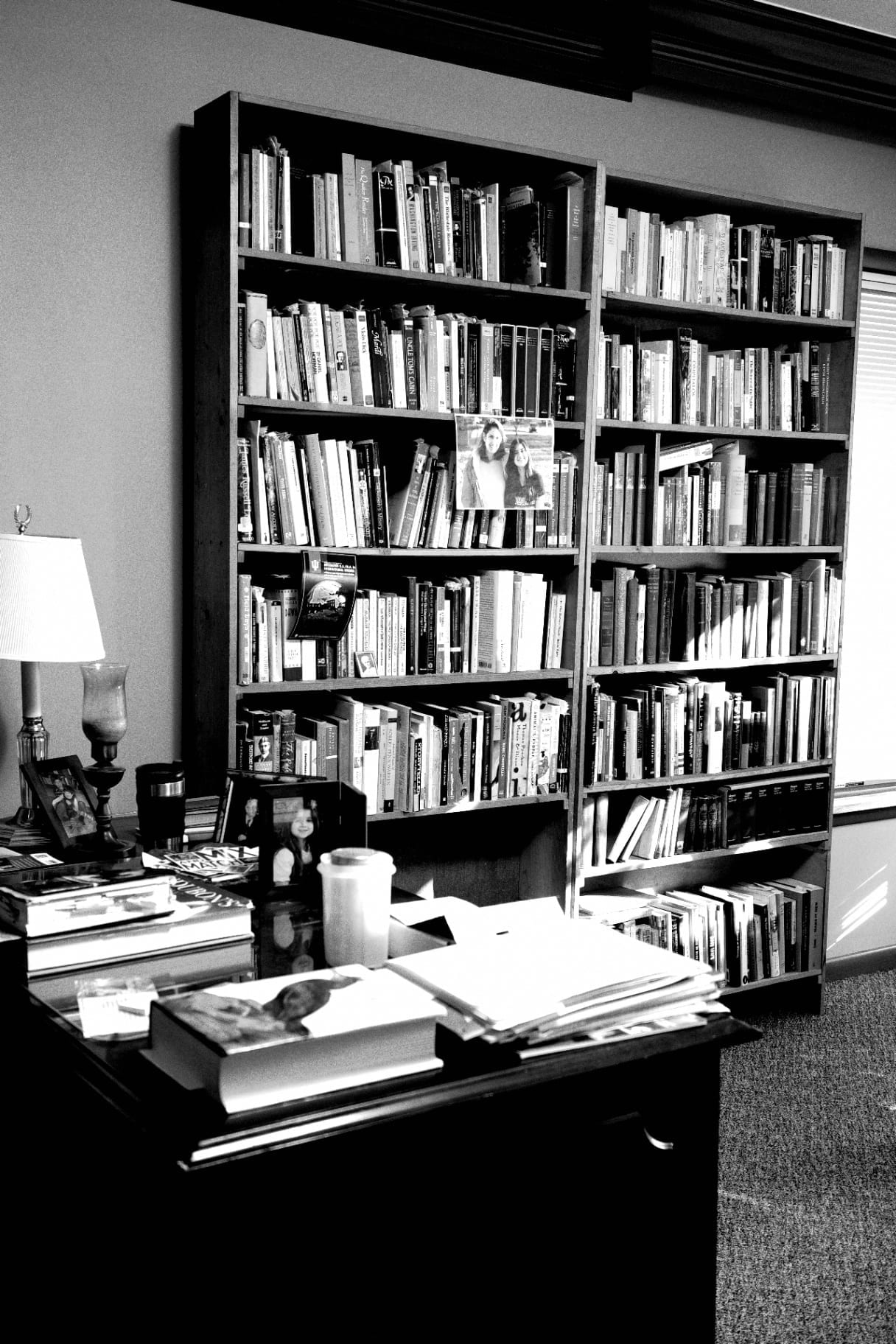 Estantes altas repletas de livros num gabinete em preto e branco
