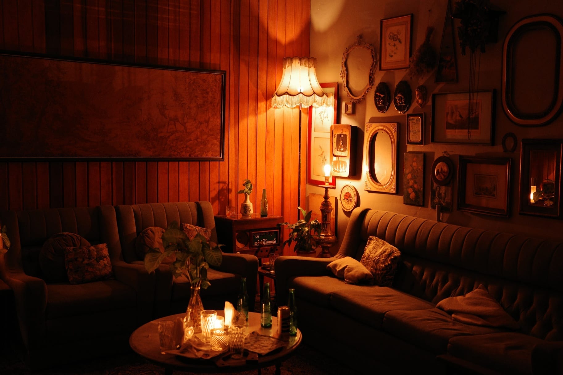 Sala vintage iluminada por abajur com parede de quadros e molduras